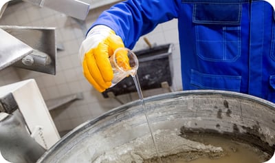 Technician pouring admixture into concrete mix for enhanced sustainability and performance in construction